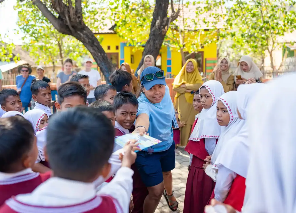 SeaTrek - Tour leader distributing book at the village